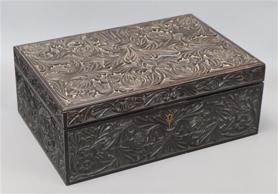 An Anglo-Ceylonese carved ebony box with ivory inlay, with specimen wood section lids to interior, 19th century length 42cm